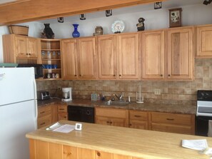A kitchen with wooden cabinets, a white refrigerator, a coffee maker, and a sink.
