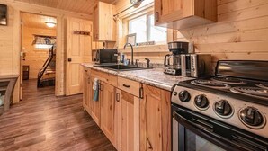 Cocina de cabaña de madera con estufa, pileta y cafetera.