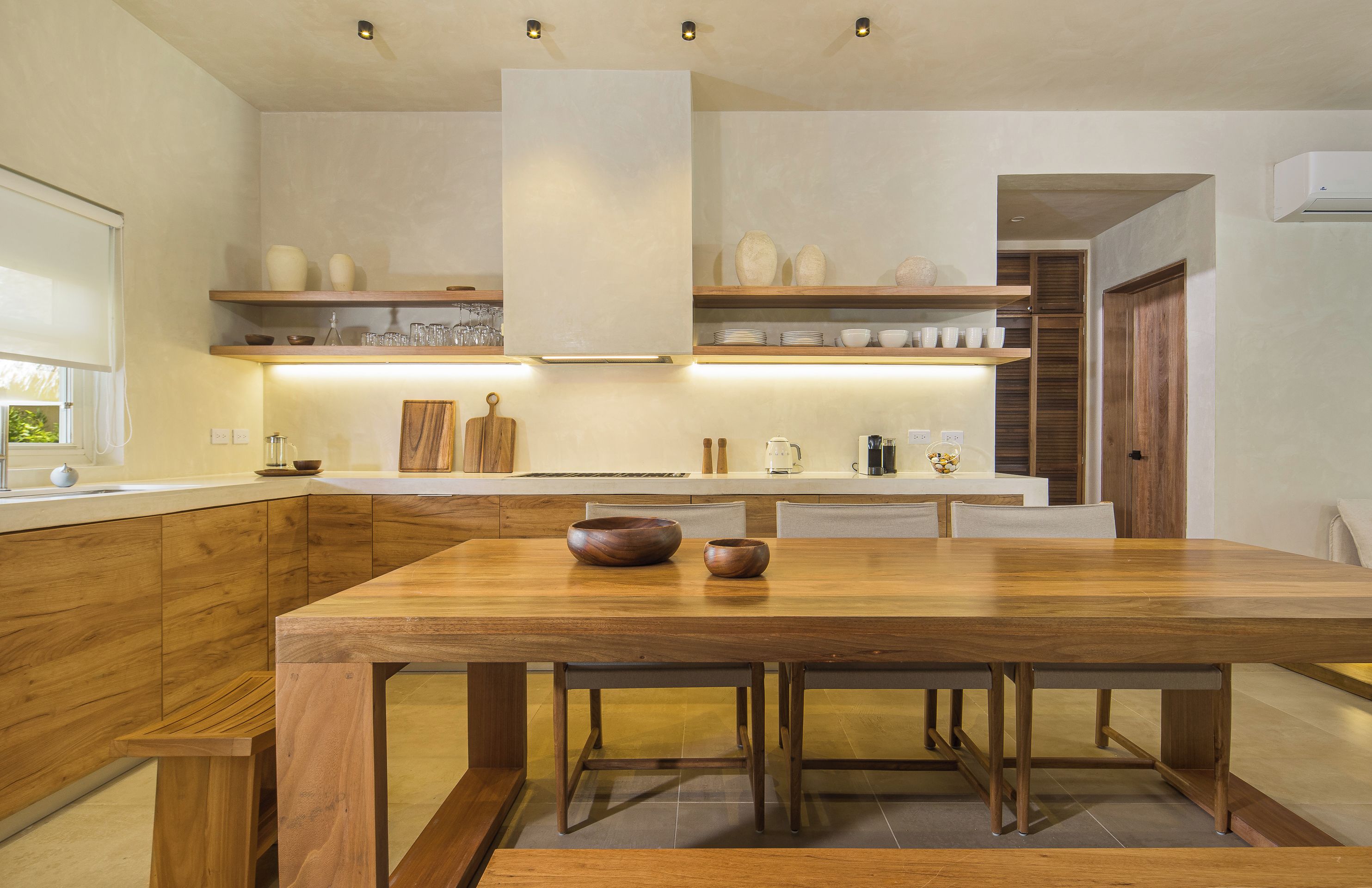 Une cuisine moderne avec des meubles en bois, un îlot central et des étagères intégrées au-dessus du plan de travail.