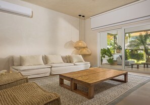 A modern living room with a sofa, a wooden coffee table, and a woven floor rug.