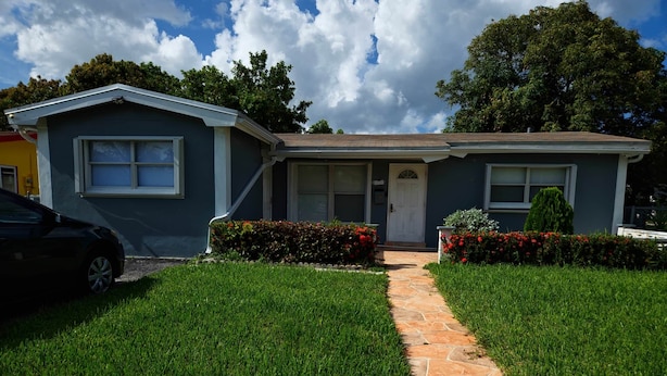A two-story house with a front porch, a stone pathway, and well-maintained lawns. - TheVacaVacationHomes (Lauderdale Lakes)