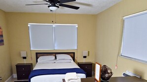 A bedroom with a bed, two bedside tables, a ceiling fan, a window with blinds, a nightstand, a rug, and a couch. - TheVacaVacationHomes (Lauderdale Lakes)