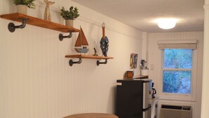 A kitchen with wooden stools, a refrigerator, and shelves with decorative items. - Cozy Nautical Getaway in Cape Neddick (Ogunquit)