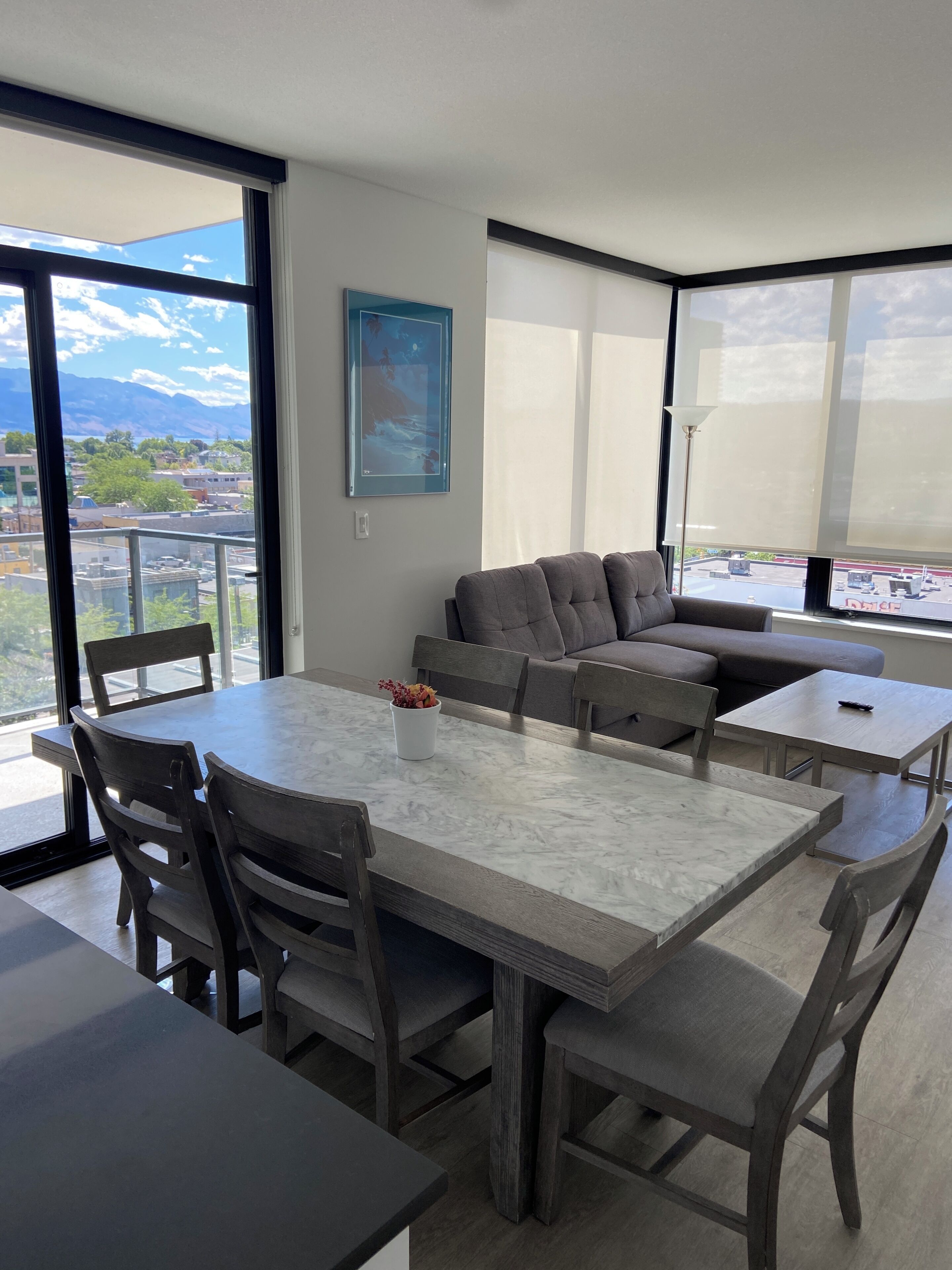 Ein modernes Wohnzimmer mit Essbereich, großen Fenstern und Blick auf die Stadt.