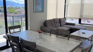 Ein modernes Wohnzimmer mit Essbereich, großen Fenstern und Blick auf die Stadt.