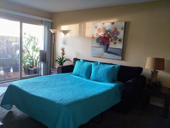 Un dormitorio con una cama grande, un cuadro en la pared y una planta en maceta.