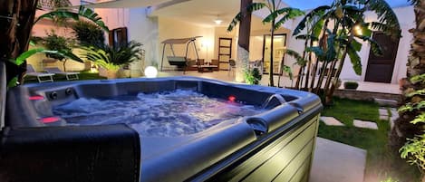 A hot tub in a garden area with a patio and outdoor furniture.