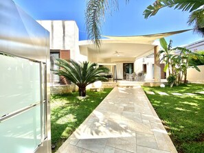 Une maison moderne dotée d’un patio, d’un palmier et d’un chemin en pierre.