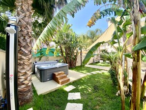 Un jardin avec un jacuzzi, un palmier et un espace aménagé.