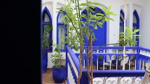 A courtyard with blue doors and white railings, surrounded by potted plants. - Hotel Riad Dar El Qdima (Essaouira)