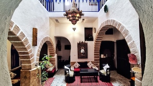 A cozy interior with a central seating area, a chandelier, and arched brick walls. - Hotel Riad Dar El Qdima (Essaouira)