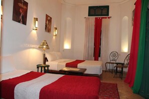 A hotel room with two beds, a table, chairs, and decorative wall sconces. - Hotel Riad Dar El Qdima (Essaouira)