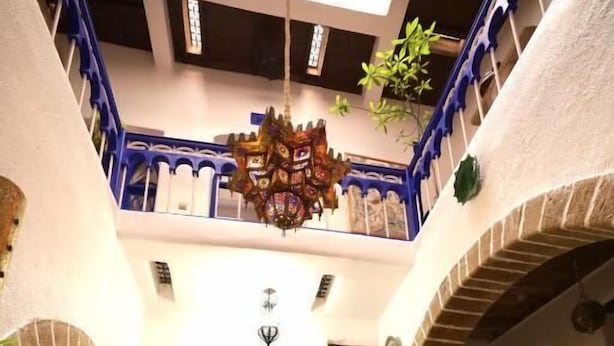 A courtyard with a central seating area, arches, and a hanging chandelier. - Hotel Riad Dar El Qdima (Essaouira)
