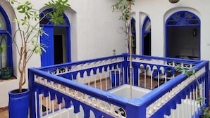 A courtyard with a blue and white railing, a hanging basket, and potted plants. - Hotel Riad Dar El Qdima (Essaouira)