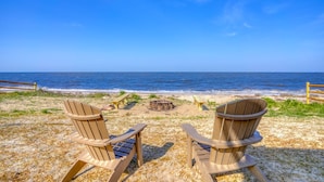 Two Adirondack chairs facing a beach with a wooden fence and a fire pit. - Secluded Beach home with amazing views.  (Milford)