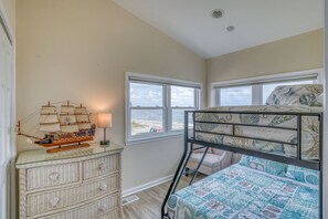 A child's bedroom with a bunk bed, a dresser with drawers, a ship model, and a view of the beach through the windows. - Secluded Beach home with amazing views.  (Milford)