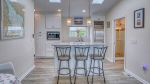 A modern kitchen with a central island, white cabinetry, and a skylight. - Secluded Beach home with amazing views.  (Milford)