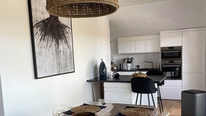 Ein moderner Essbereich mit einem langen Tisch, gewobenen Tischsets und einer hängenden Leuchte.
