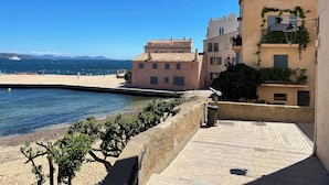 Ein Küstengebäude mit einem Ziegeldach, einem gepflasterten Weg und Blick aufs Meer.