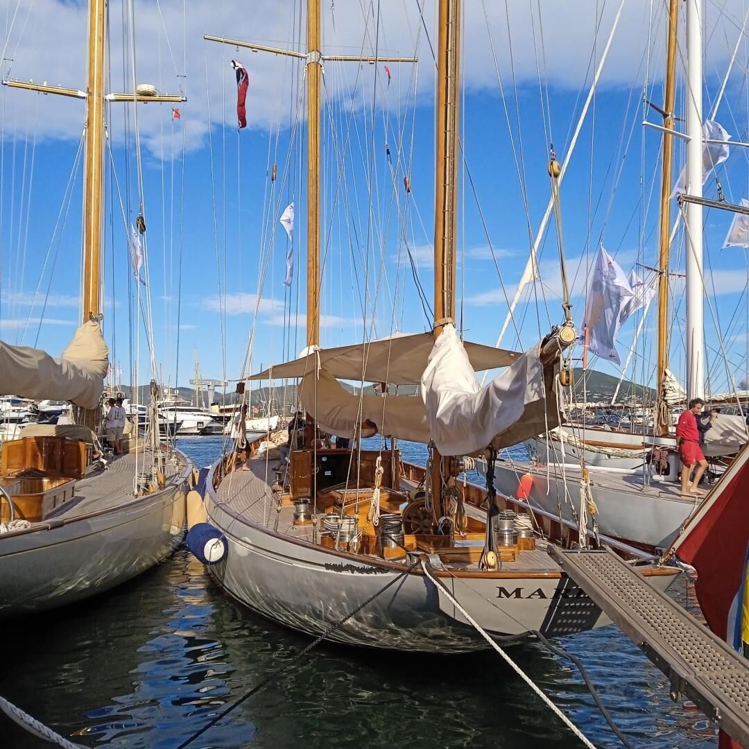Marina com vários veleiros atracados, exibindo mastros, equipamentos de navegação e decks de madeira.