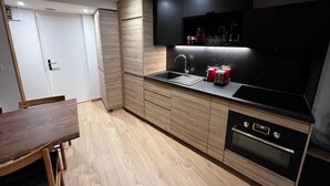 Una cocina moderna con armarios de madera, encimera negra y horno empotrado.