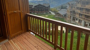 Un balcón de madera con vistas a un paisaje montañoso y edificios.