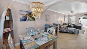 Un coin repas avec une table en bois dressée pour quatre personnes, un lustre et un tableau accroché au mur.