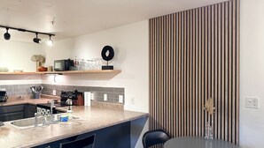 Une cuisine moderne avec un îlot central, des chaises noires et une table ronde.