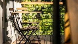 Un balcón con mesa y sillas, con vistas a una zona verde.