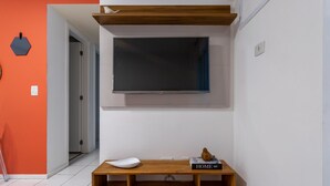 A modern living room with a flat-screen TV mounted on the wall, a wooden bench with a white cushion, and a book titled "HOME" on the bench. - Beauty at Recreio For 5 Peopple Sa201 (Rio de Janeiro)