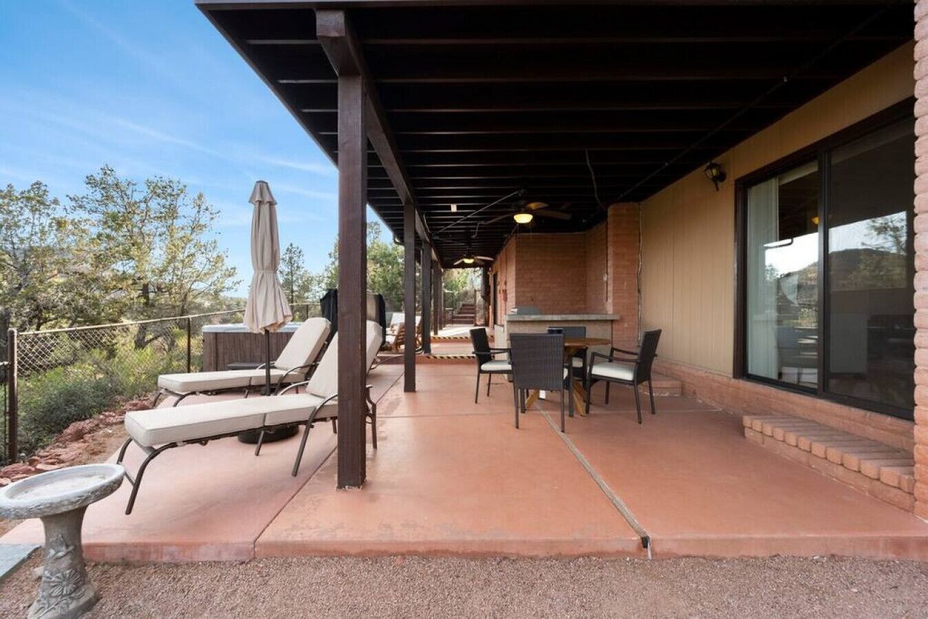 Un patio cubierto con sillones, una mesa y una zona de barbacoa.