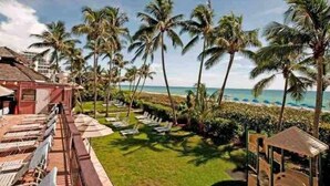 A resort with a poolside area, palm trees, and a view of the ocean. - Ocean Front Condo - Walk out to the Sand (Miami)
