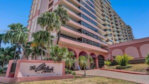 A high-rise hotel with multiple balconies, a sign for 'The Carlyle Hotel', and a landscaped entrance area. - Ocean Front Condo - Walk out to the Sand (Miami)