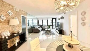 A modern living room with a fireplace, a large chandelier, and a sofa set. - Ocean Front Condo - Walk out to the Sand (Miami)