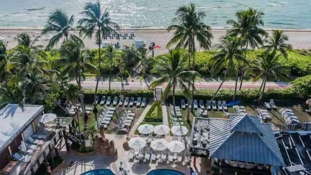 A resort with a pool area, lounge chairs, and palm trees. - Ocean Front Condo - Walk out to the Sand (Miami)