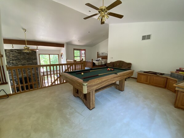 A spacious living area with a pool table, a ceiling fan, and a stone fireplace. - Riverside/Fishing/Arcade/Pool Table/Disk Golf/Fire Pit/Basketball/Pets/WiFi/UTV (Marion)