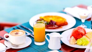 Een ontbijt met een kop koffie, een glas sinaasappelsap, een bord fruit en een karaf water.