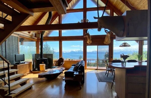 Enjoy a panoramic view of the surrounding mountains from the large windows in this living area, which features a fireplace, comfortable seating, and a dining table.