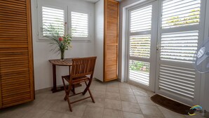 Een hoekzaal met een houten tafel en stoel, een bloempot en een ventilator.