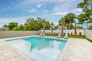 A rectangular swimming pool with a herringbone tile border, surrounded by a white fence, and adjacent to a white building with a blue roof. - 30 A-mazing! Private Heated Pool, 4 bedroom, 6 Seater Golf Cart & Bikes! (Santa Rosa Beach)