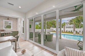 A spacious living area with a view of a swimming pool and outdoor furniture. - 30 A-mazing! Private Heated Pool, 4 bedroom, 6 Seater Golf Cart & Bikes! (Santa Rosa Beach)