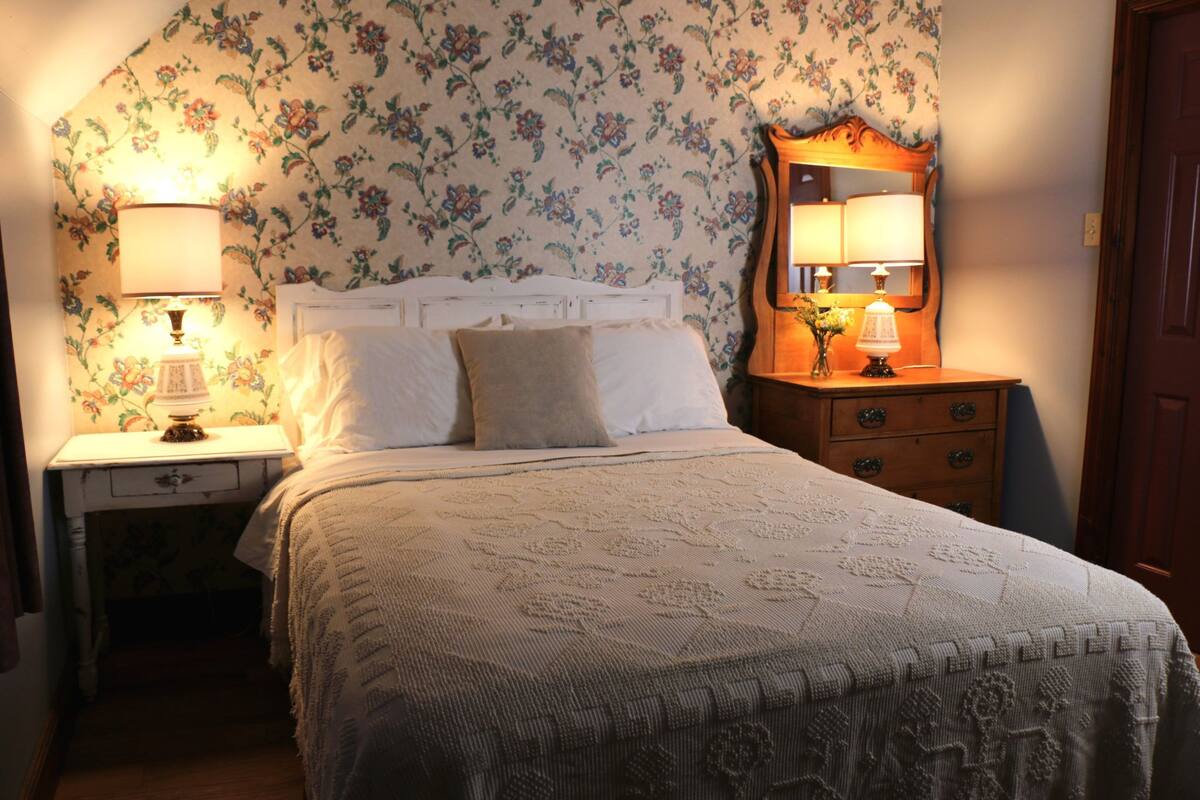 A bedroom with a bed, two bedside tables, a nightstand, a dresser, and a mirror.