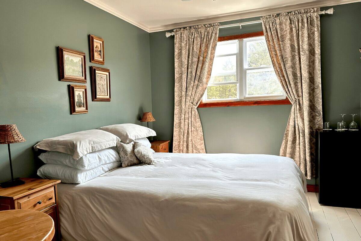 A bedroom with a bed, bedside tables, a lamp, and curtains.