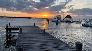 Een houten steiger die zich uitstrekt over kalm water, met een zonsondergang op de achtergrond.