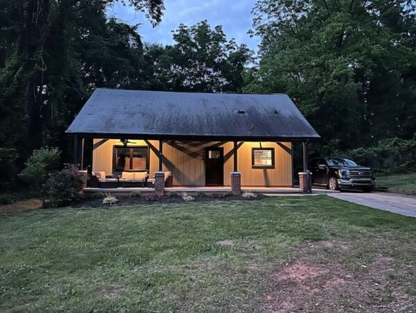A wooden cabin with a porch, a covered seating area, and a vehicle parked in front. - Modern 3 BR house in Belmont (Belmont)