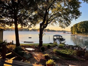 A lakeside patio with a gazebo, outdoor seating, and a dock.
