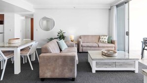 Ein modernes Wohnzimmer mit zwei Sofas, einem Couchtisch, einem Esstisch mit Stühlen und einem großen Spiegel an der Wand.