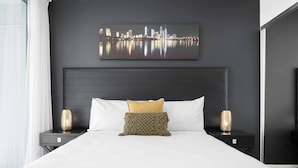 Ein modernes Hotelzimmer mit einem großen Bett, dunklen Wänden und einem Stadtbild über dem Kopfteil.