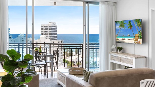 Ein modernes Hotelzimmer mit Balkon, großen Fenstern und Meer- und Stadtblick.