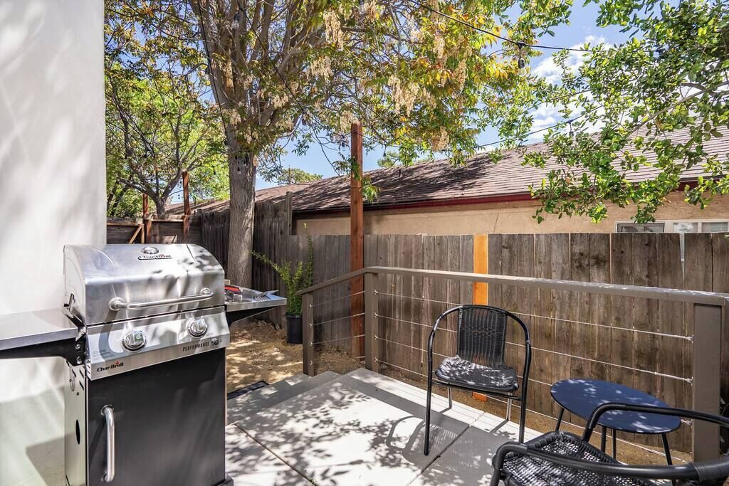 Un patio con una parrilla, una silla y una mesa.